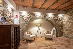 Habitación con una pared de piedra con 2 sillas y una lámpara. en Hostal Can Xicu, en Capmany