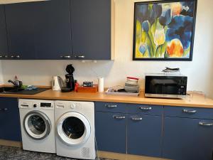 een keuken met een wasmachine en een magnetron bij Privatzimmer Haus Grünewald in Solingen