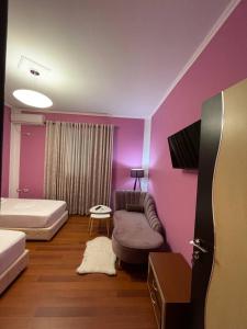 een slaapkamer met paarse muren en een bed en een bank bij Bora Hotel in Gjirokastër