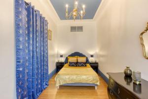 een slaapkamer met een bed met blauwe gordijnen en een kroonluchter bij « La cour royale » appartement prestigieux à 50m du château de Versailles in Versailles