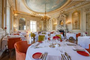 ムルソーにあるChâteau & Spa de la Cueilletteの白いテーブルと椅子、シャンデリアのあるレストラン