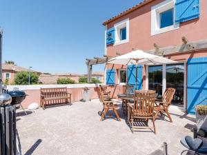 a patio with a table and chairs and an umbrella at Appartement T3 avec terrasse, parking, lave-vaisselle à Narbonne-Plage - FR-1-409-104 in Narbonne-Plage