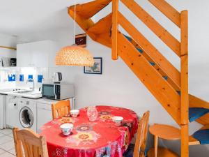 uma cozinha com uma mesa vermelha com cadeiras e uma escada em Villa Narbonne-Narbonne Plage-Narbonne Plage, 3 pièces, 4 personnes - FR-1-409-112 em Narbonne Plage