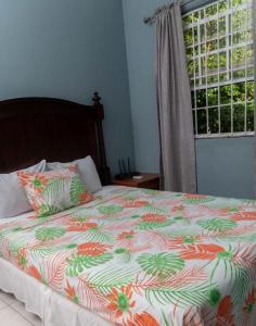 a bed with a colorful comforter and a window at Bougainvillea Apartments in Castries