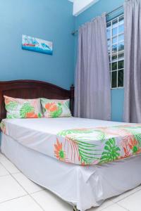 Bougainvillea Apartments في كاستريس: سرير في غرفة بجدران زرقاء ونافذة