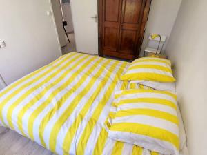 uma cama com lençóis e almofadas de listras amarelas e brancas em Appartement Six-Fours-les-Plages, 2 pièces, 4 personnes - FR-1-316-232 em Six-Fours-les-Plages