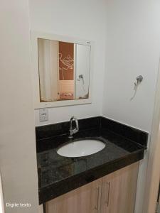 ein Bad mit einem Waschbecken und einem Spiegel in der Unterkunft Village das águas. in Barra do Piraí