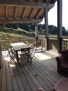 a wooden deck with a table and chairs on it at Les 7 laux immobilier chalet F in Prapoutel