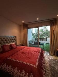 a bedroom with a red bed and a large window at Lyoan home in Ḩayl Āl ‘Umayr