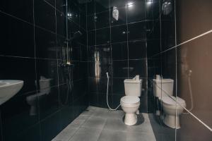 a black tiled bathroom with two toilets and a sink at villa mediterania kerobokan buleleng in Babakan Sangsit +20 photos