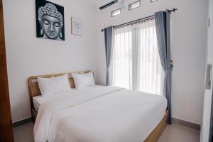 a bedroom with a large white bed and a window at villa mediterania kerobokan buleleng in Babakan Sangsit