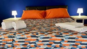 1 dormitorio con 1 cama con almohadas de color naranja y 2 lámparas en Benvenuti a Casa Sicilian Apartment Palermo, en Termini Imerese