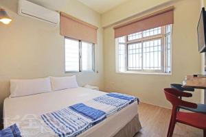 a small bedroom with a bed and two windows at FUNSUMMER in Green Island