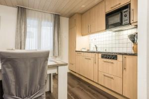 une cuisine avec des placards en bois, une table et une chaise dans l'établissement Apartment Babice 2.0 - GRIWA RENT AG, à Grindelwald