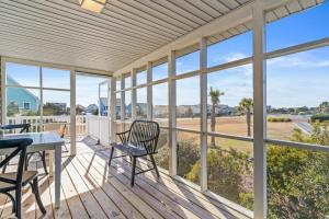 a screened porch with a table and chairs and windows at Dunebug Cottage 319 Sandpiper Lane home in Holden Beach
