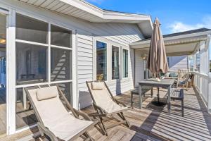a deck with chairs and a table and an umbrella at Dunebug Cottage 319 Sandpiper Lane home in Holden Beach +35 photos