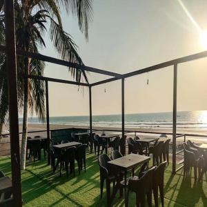 a restaurant with tables and chairs on the beach at zoz Mg in Old Goa