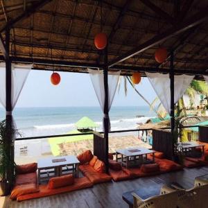 a pavilion with tables and a view of the beach at zoz Mg in Old Goa