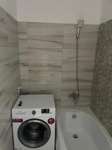 a bathroom with a washing machine and a bath tub at Bucium Comfort Apartaments in Iaşi