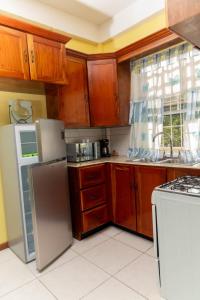 una cocina con armarios de madera y electrodomésticos blancos en Bougainvillea Apartments, en Castries