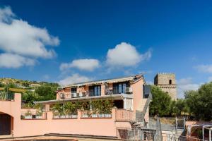 un edificio rosa con una torre en el fondo en Casa Vacanze Maraldo, en Marina di Camerota