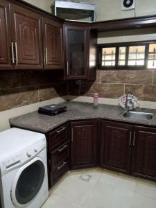 uma cozinha com armários de madeira, um lavatório e uma máquina de lavar louça em الشقة العائلية الحديثة em Amã