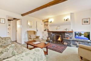 a living room with a fireplace and a tv at Crag Cottage in Coniston