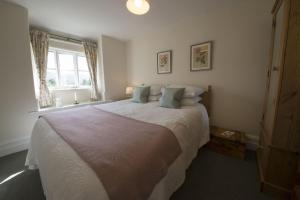 a bedroom with a large white bed with a window at Crag Cottage in Coniston