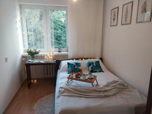 een slaapkamer met een bed met blauwe kussens en een tafel bij Apartament Kolberga II in Sopot