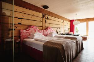 a bedroom with two beds and a wooden wall at Small Luxury Hotel of the World - DasPosthotel in Zell am Ziller