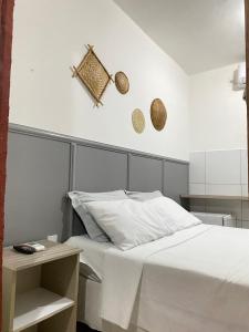 1 dormitorio con cama blanca y mesita de noche en Pousada Asa Branca, en Piranhas