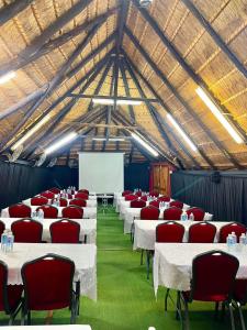 Keeme-Nao Self Catering Apartments في غابورون: قاعة اجتماعات مع طاولات بيضاء وكراسي حمراء