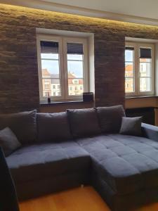 um sofá numa sala de estar com três janelas em Rynek 23 LUX, apartament z widokiem na ratusz Starego Miasta em Gliwice