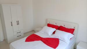 a bedroom with a white bed with a red bow on it at T2 no Recanto d' fonte francês in Mindelo