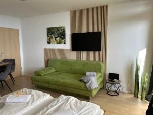 a living room with a green couch and a flat screen tv at Ferienwohnung Uns Uwe in Freyung