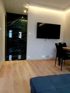 uma sala de estar com uma mesa e uma televisão na parede em Rynek 23 LUX, apartament z widokiem na ratusz Starego Miasta em Gliwice