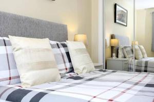 sypialnia z łóżkiem z białymi i czarnymi poduszkami w obiekcie Edinburgh Apartment near University of Edinburgh - Elforma w Edynburgu