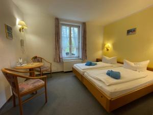 a bedroom with two beds and a table and a window at Hotel Gutshaus Kajahn in Gustow