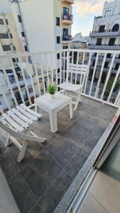 d'une terrasse avec 2 chaises et une table sur un balcon. dans l'établissement Amnesia Apartment, à San Pawl il-Baħar