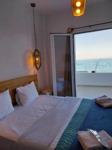 Galazio Seaside Luxury Rooms & Coffee Shop في بلاتامون: غرفة نوم مع سرير وإطلالة على المحيط