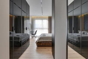 1 dormitorio con 2 camas, silla y espejos en Zajezdnia Wrzeszcz 2 by Grand Apartments en Gdansk