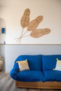 タオルミーナにあるTaormina Holiday Apartmentの青いソファ、葉絵が壁に描かれたリビングルーム