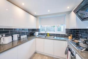 a kitchen with white cabinets and a window at *RA75L* For your most relaxed & Cosy stay + Free Parking + Free Fast WiFi * in Hunslet