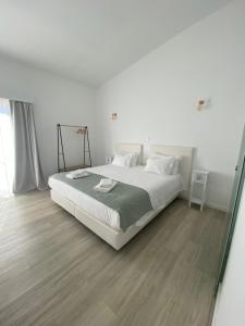 una camera da letto bianca con un letto e uno specchio di Casa das Marias a Vila Nova de Milfontes Altre 38 foto