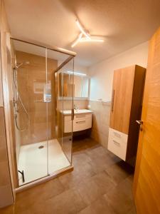 y baño con ducha acristalada y lavamanos. en Appartement am Moosbach, Fieberbrunn - St. Jakob, en Sankt Jakob in Haus