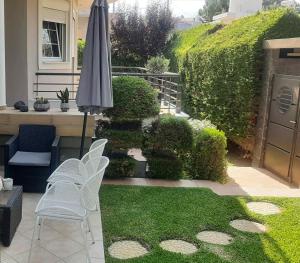 eine Terrasse mit einem Sonnenschirm, Stühlen und Gras in der Unterkunft Villa Ariadni in Patras