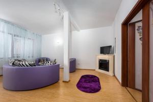 a living room with a purple couch and a tv at Central Apartament Predeal Nr 6 in Predeal