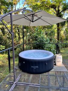 an umbrella next to a hot tub on a patio at Roble Coral Glamping in Sarapiquí