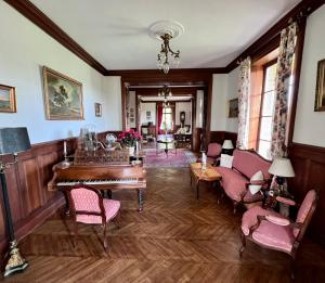 ein Wohnzimmer mit einem Klavier und Stühlen in der Unterkunft Chateau du Gue aux Biches in Bagnoles de l'Orne