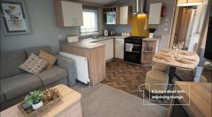 een kleine keuken en een woonkamer met een bank en een tafel bij 9 The Meadows FallBarrow Park in Bowness-on-Windermere